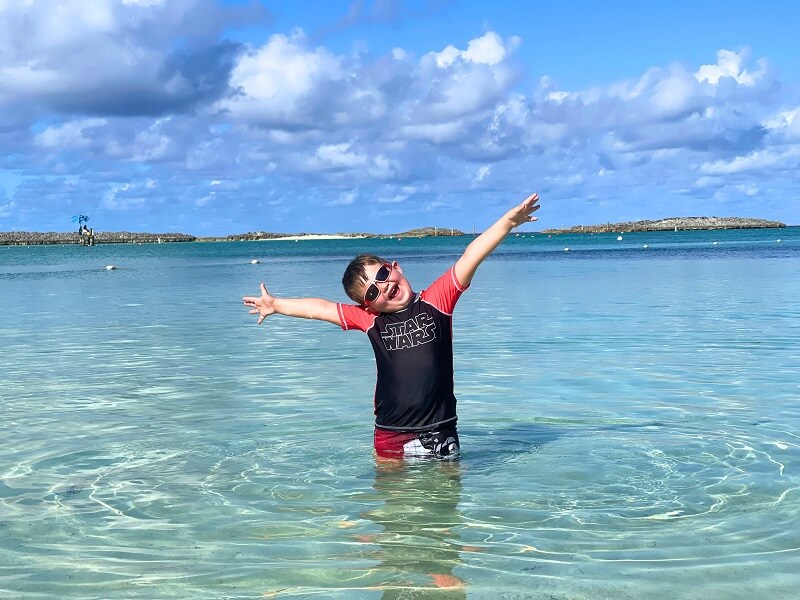 Castaway Cay with Kids - excited young boy with open arms in the water