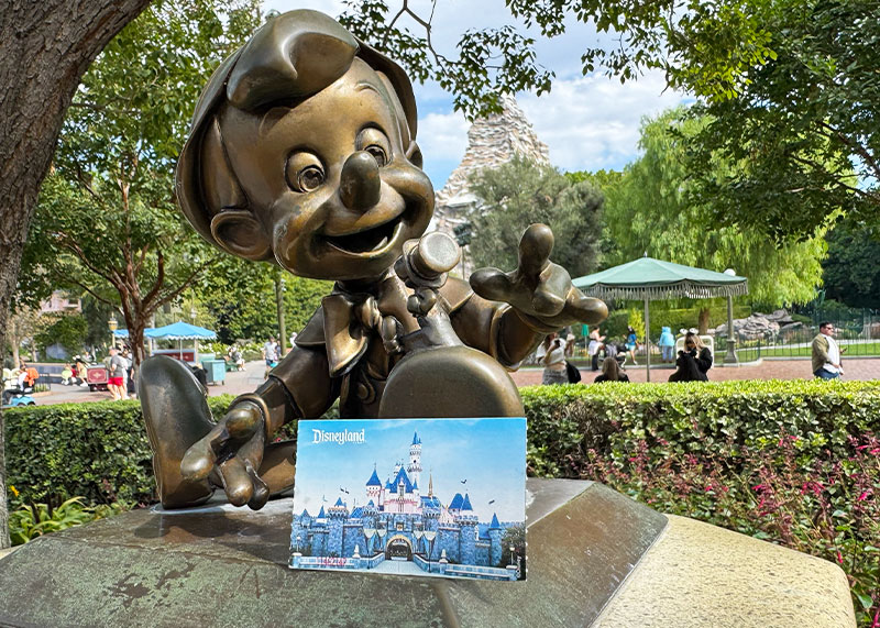 Your Guide to Disneyland's Theme Park Reservation System- Disneyland ticket with Pinocchio statue