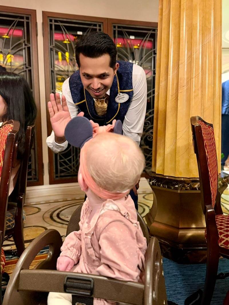 disney cruise with a baby - crew member giving a high five to a baby