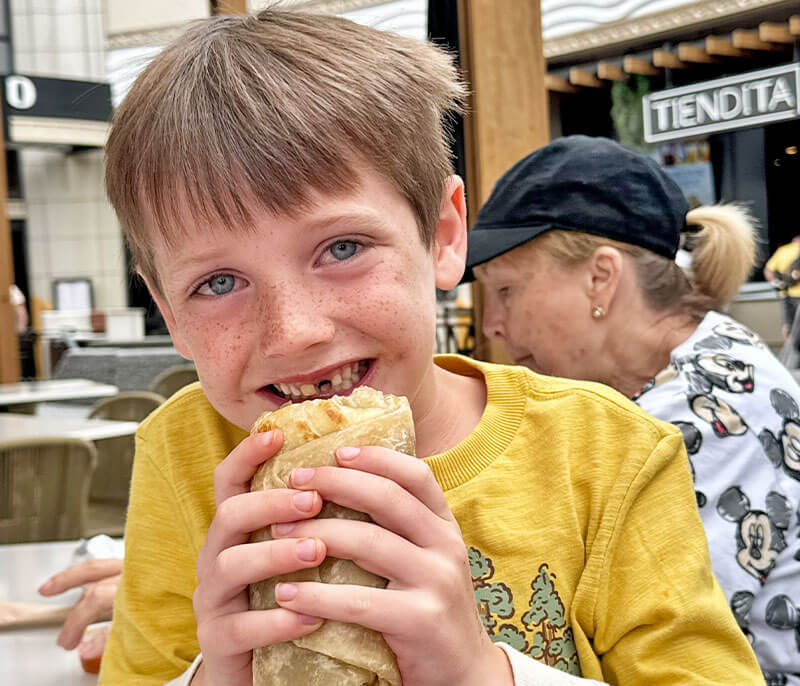 The Yummiest Places to Fill Up on Breakfast at Disneyland - Boy eats a burrito in Downtown Disney
