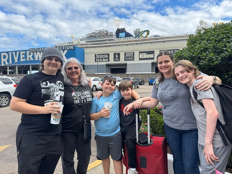 Cruises from New Orleans - Family stands in front of RIverwalk Outlets in New Orleans with Cruise Ship in View